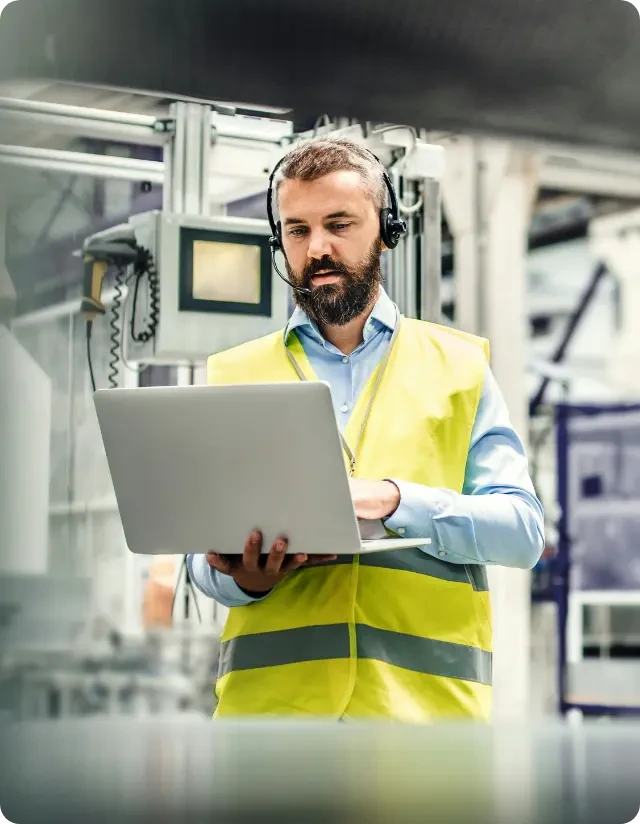 Service technician using laptop to access digital aftermarket parts catalog in industrial facility