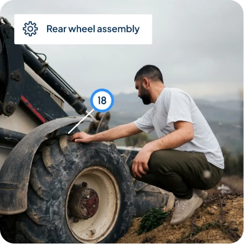Technician inspecting rear wheel assembly of heavy machinery